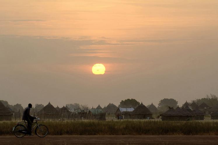 Man bicycling at sunset in South Sudan.